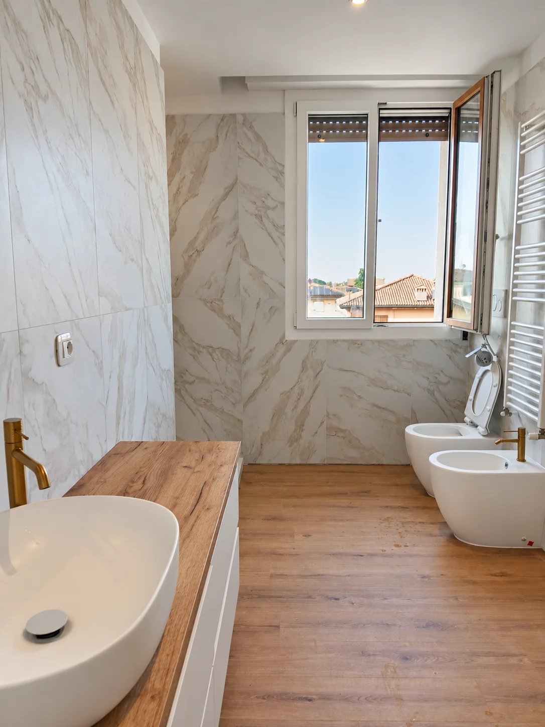 Toni caldi in bagno. Superfici effetto marmo, legno e dettagli dorati.