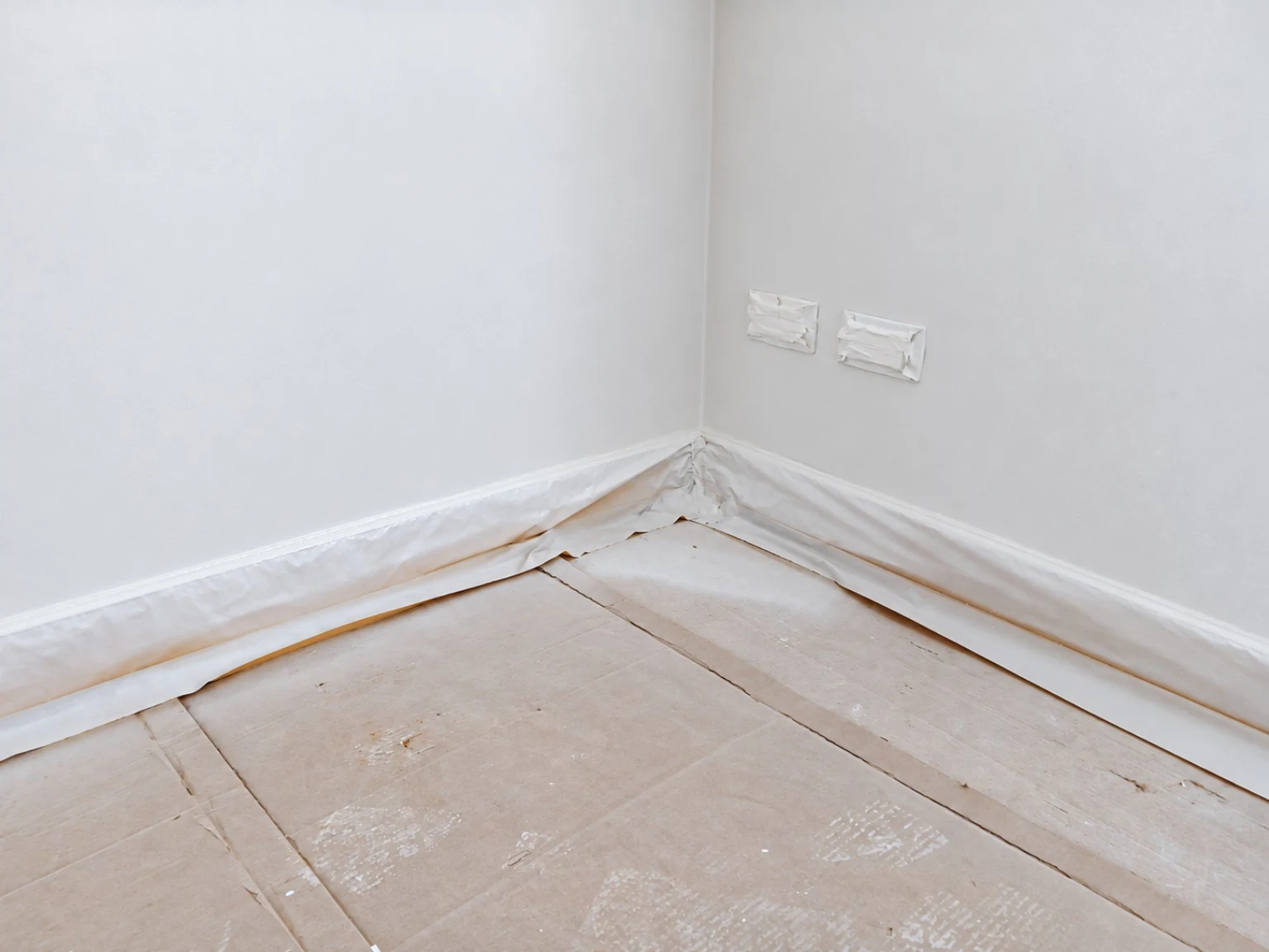 Protezione dei pavimenti. Pavimento, battiscopa e punti elettrici coperti durante la pittura.